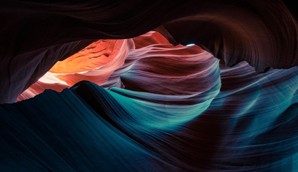 Colorful sandstone formations with sunlight filtering through in a slot canyon.