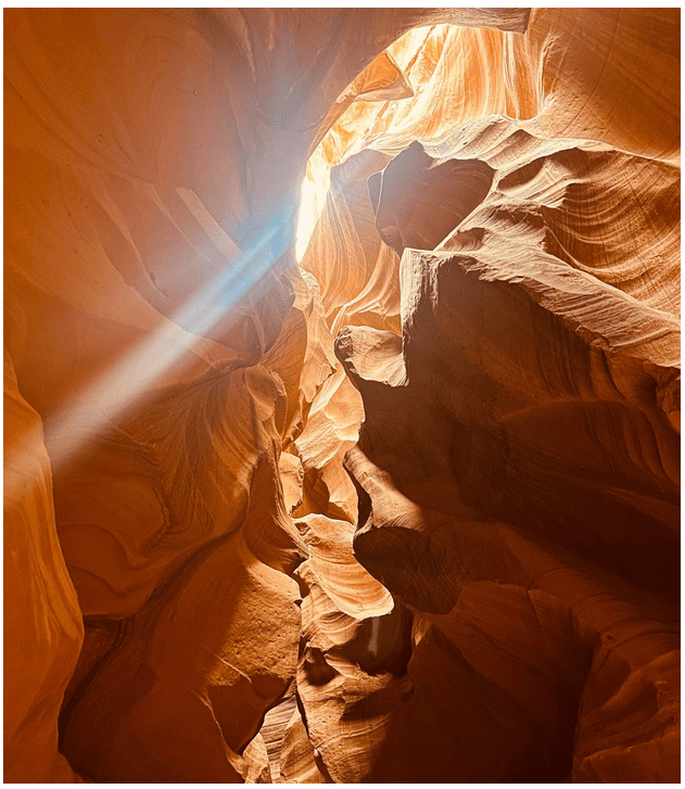 Sunlight beams into narrow orange-red sandstone canyon walls.