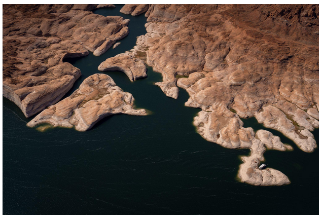 Aerial view of rocky desert terrain with dark green water in narrow channels.