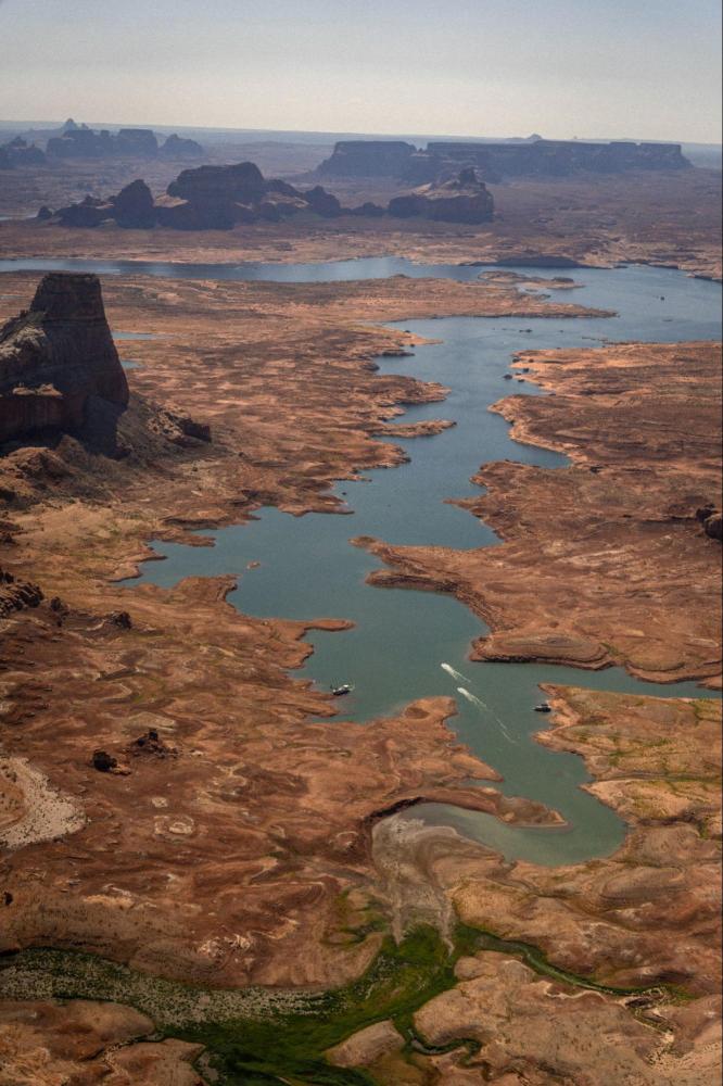Aerial view of a winding river through dry, rocky terrain under a hazy sky.