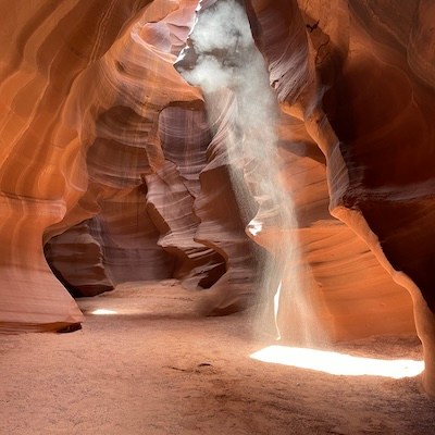 Sunlight beams into a narrow, red sandstone canyon.