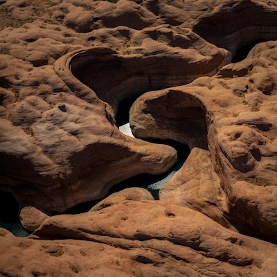 Eroded sandstone formations with winding water-filled crevices.