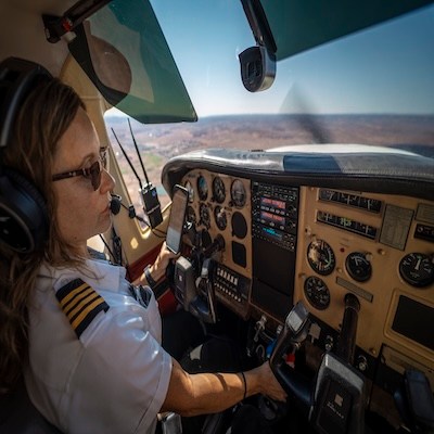 Pilot in cockpit operating aircraft controls during flight.