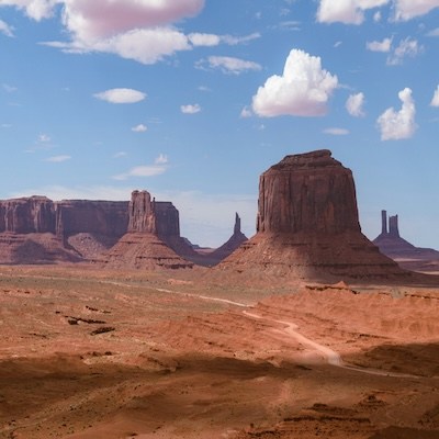 Monument Valley with large red rock formations and a cloudy sky.