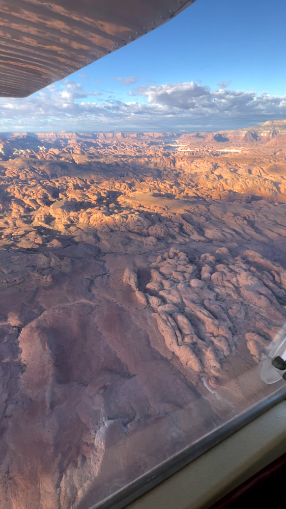Aerial view of reddish, rocky landscape from an airplane window.