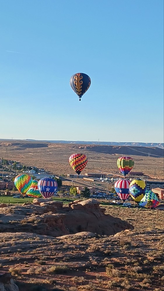 Colorful hot air balloons flying over a desert landscape.