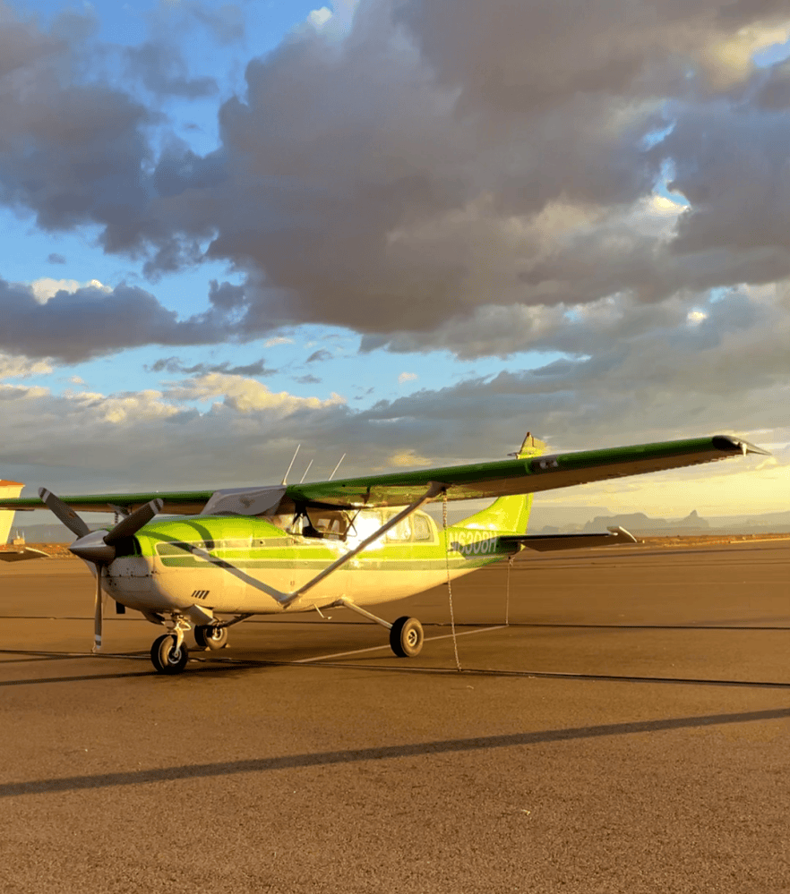 Green and white Antelope Air airplane on the tarmac at sunset.